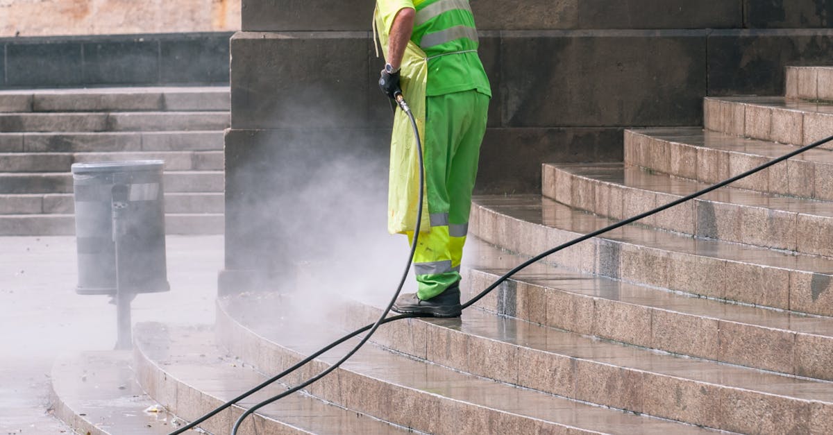 A street worker pressure washes stone stairs in a public park, ensuring cleanliness and safety.