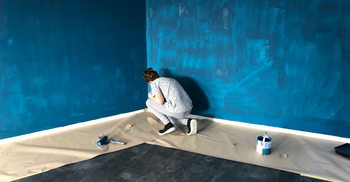 A woman painting a blue wall indoors for a home renovation project.