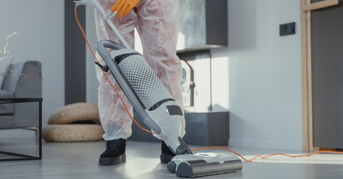 A person in protective attire cleaning a modern room with a vacuum. Bright and tidy atmosphere.