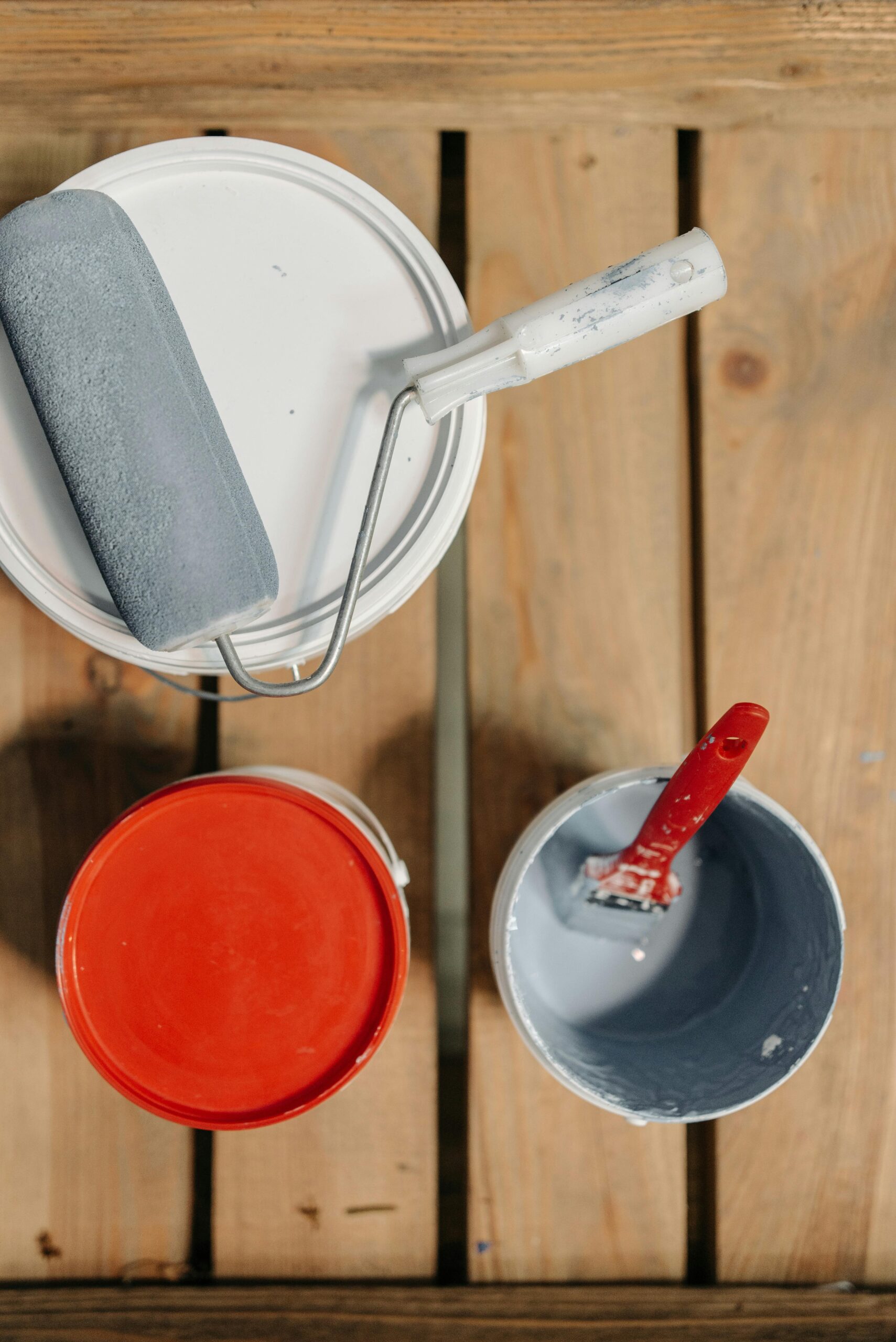 Paint cans and brushes arranged on wooden boards, ready for renovation work.